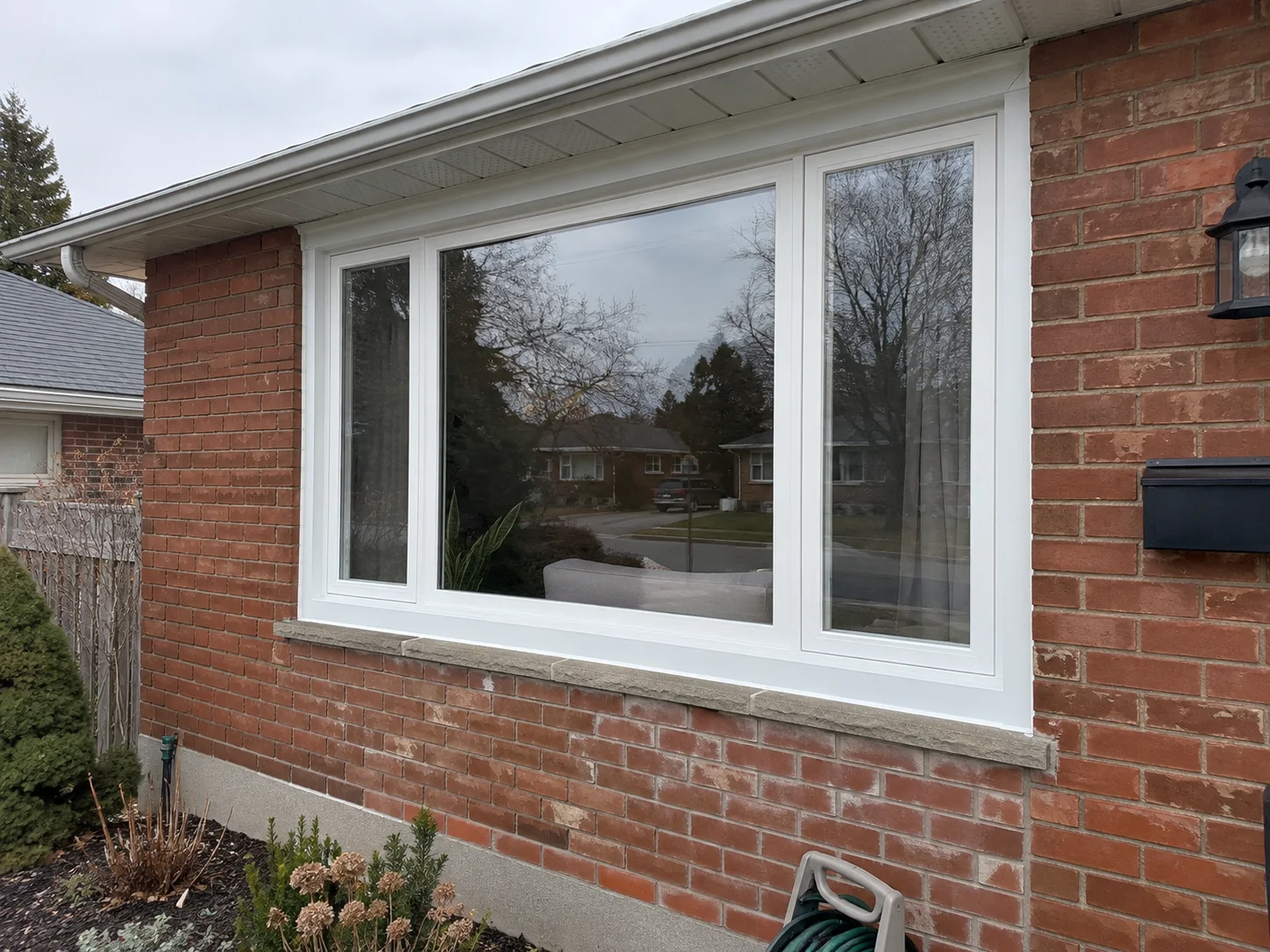 White replacement windows on a red-brick bungalow
